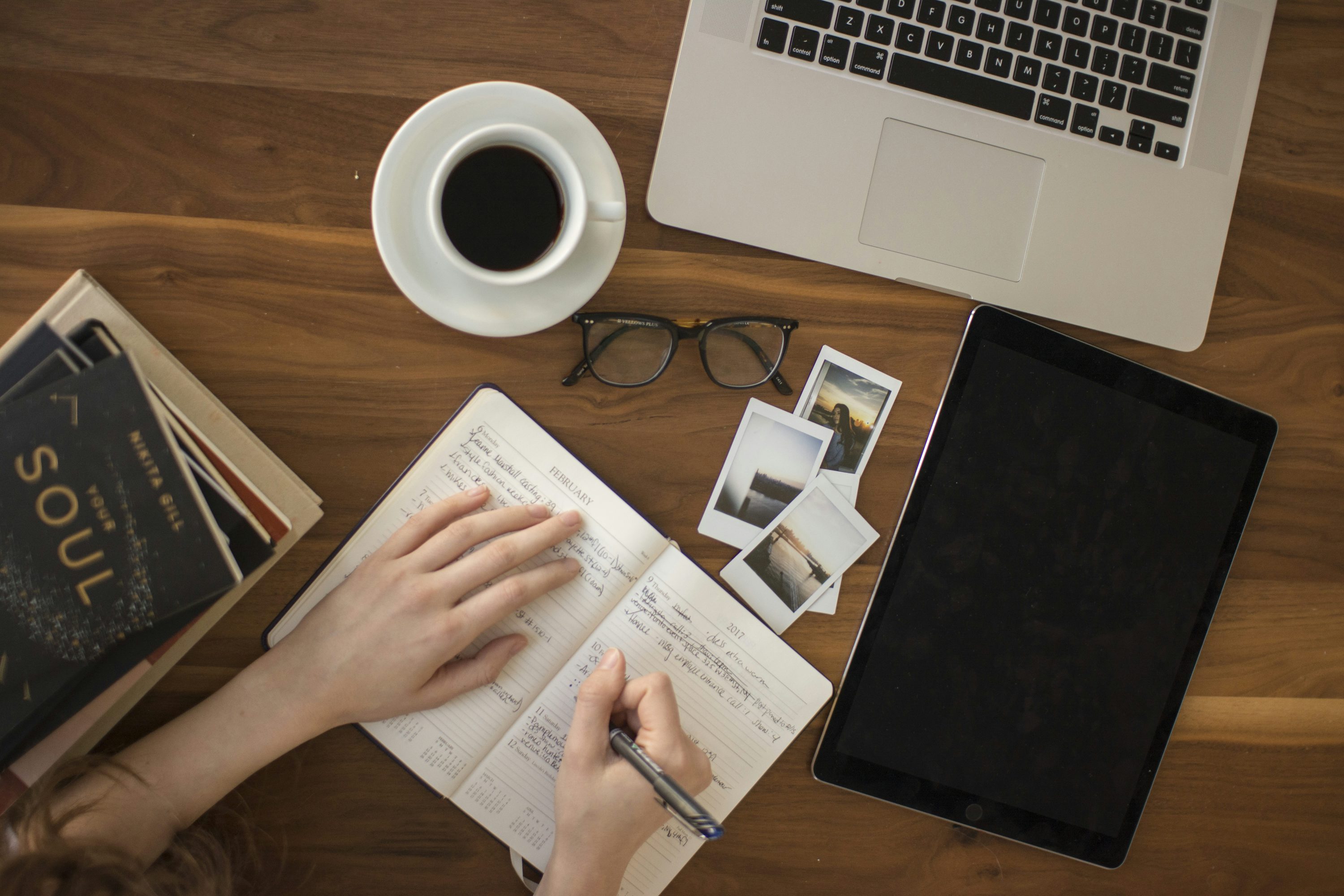 A person writing in a notebook at a wooden table